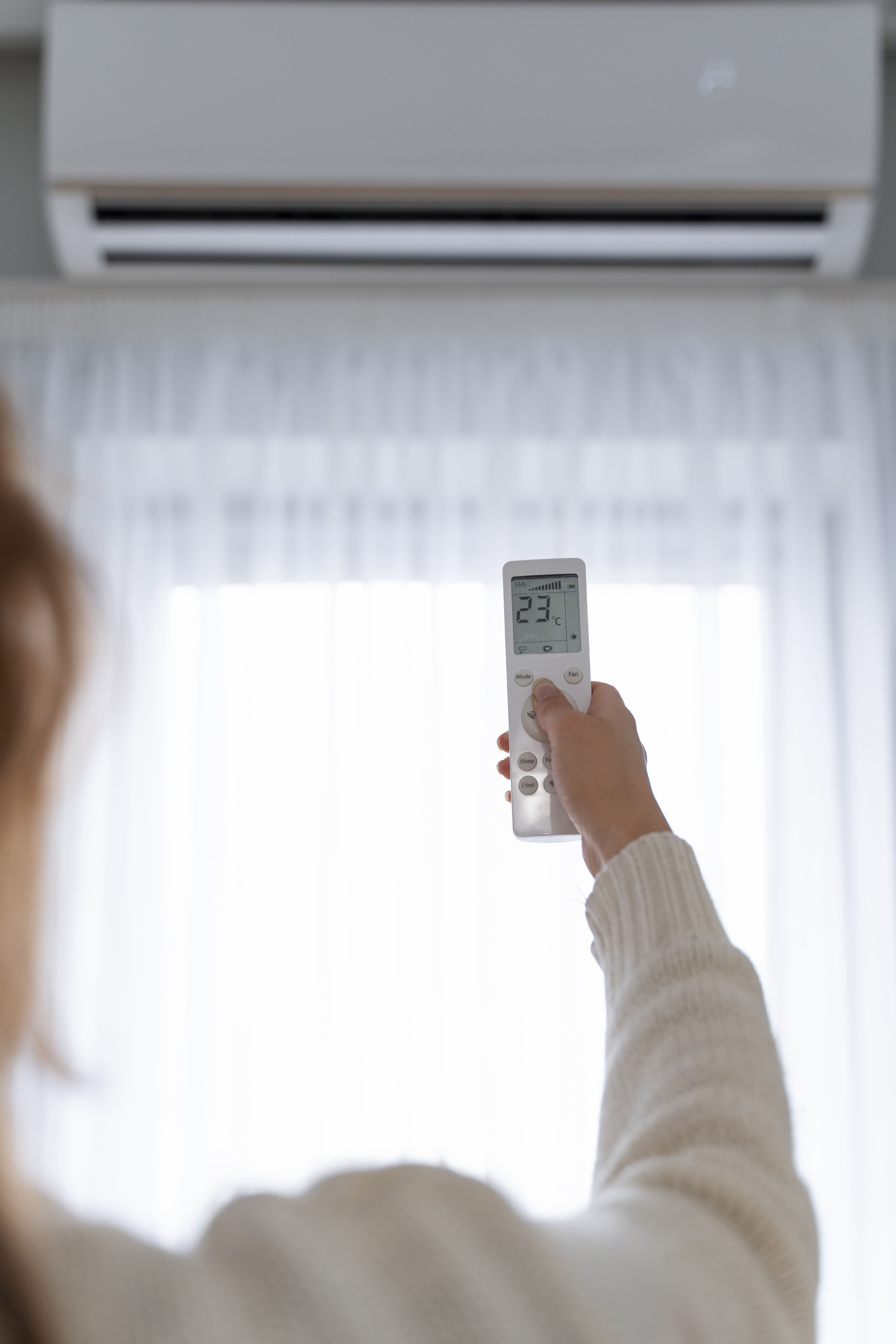 A woman setting an air-conditioner to 25 degree Celcius